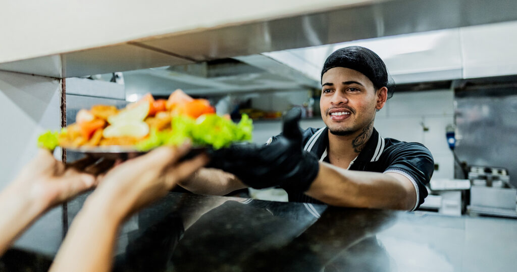 chef handing off food in the kitchen